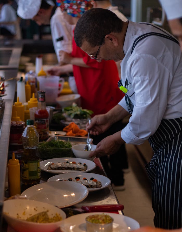 Chef expertly plates dishes in a bustling kitchen, showcasing culinary skills and preparation.