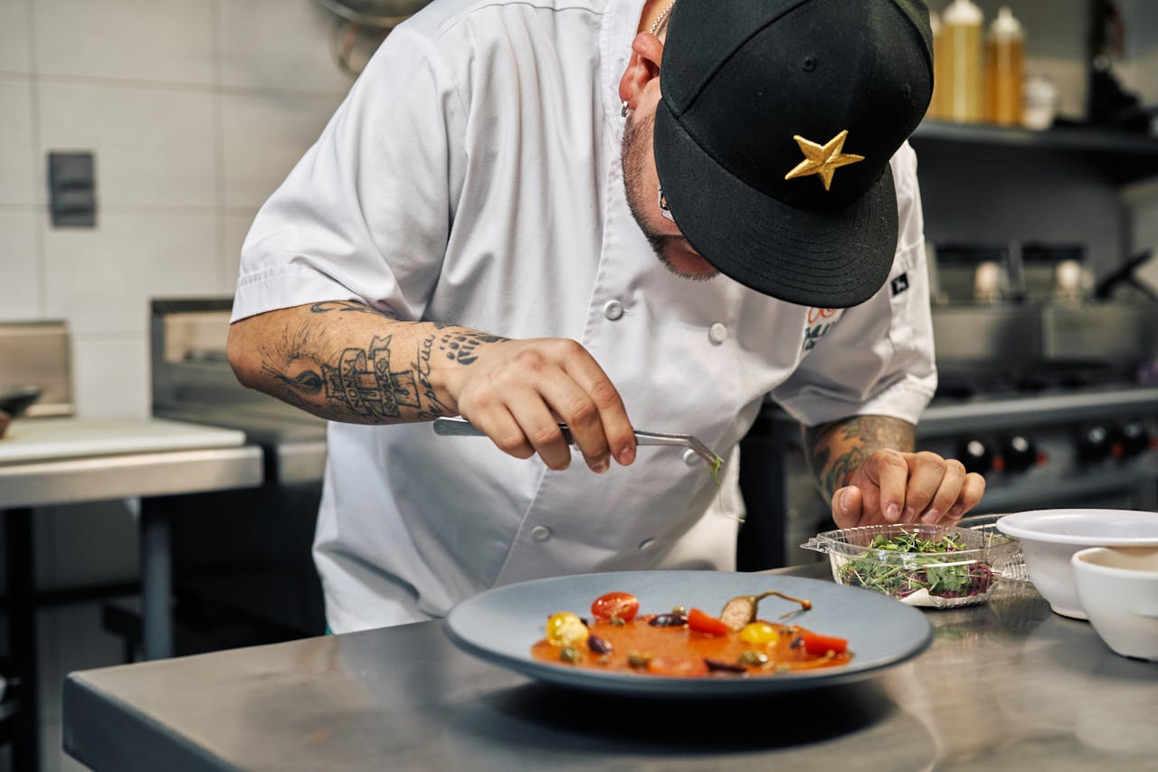Close-up of a chef in a professional kitchen garnishing a gourmet dish with precision.