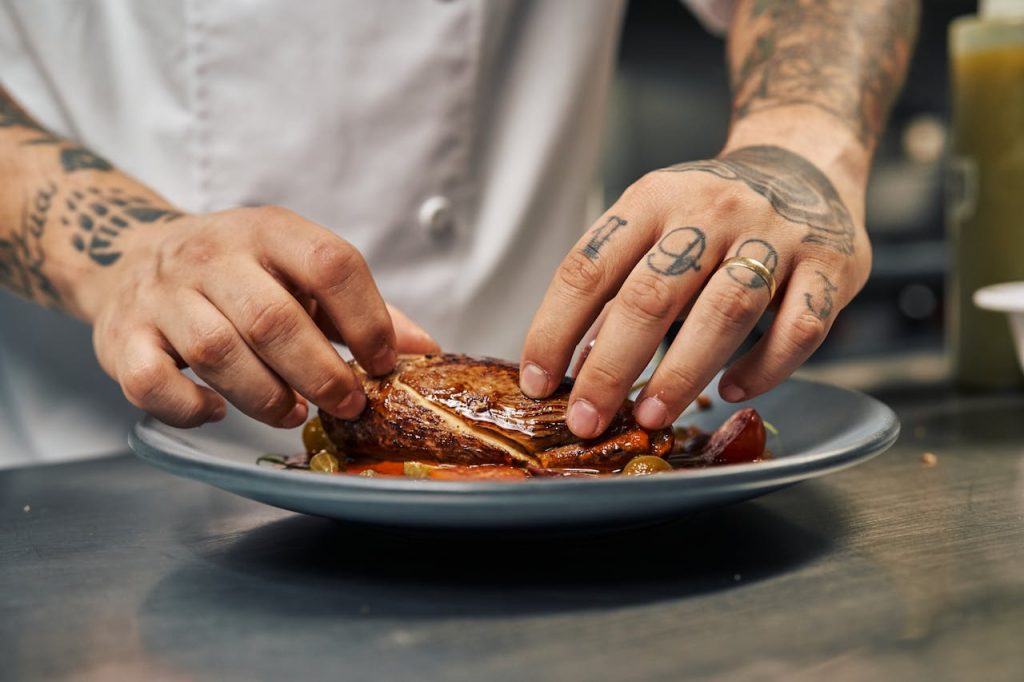 Chef artfully arranging a gourmet dish on a plate, showcasing culinary creativity.