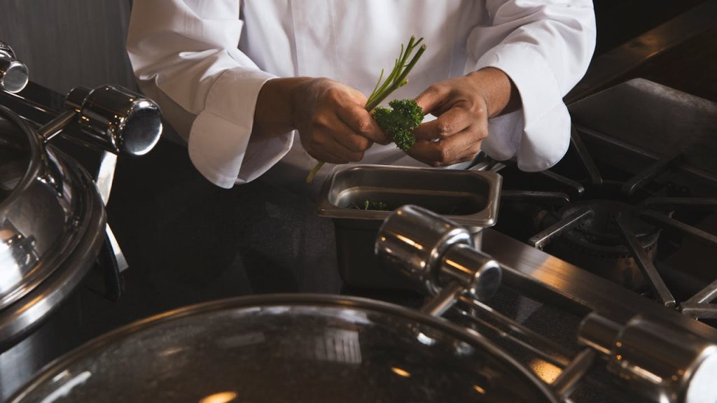 Close-up of a chef preparing parsley in a professional kitchen setting.