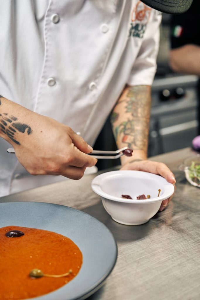 Chef preparing a gourmet dish in a kitchen with precision.